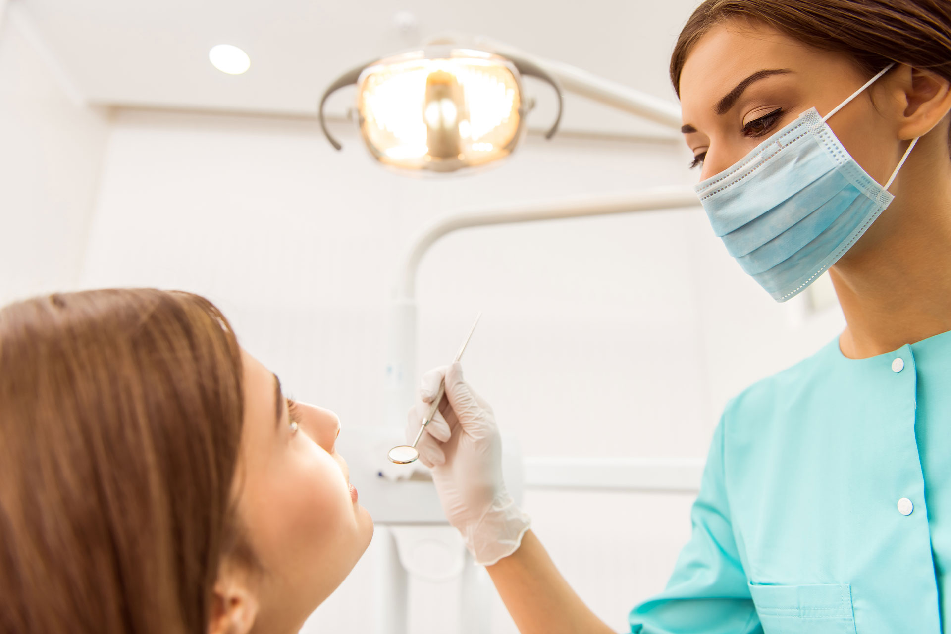 Dentiste qui examine une patiente un fauteuil de DENTELITE Pro